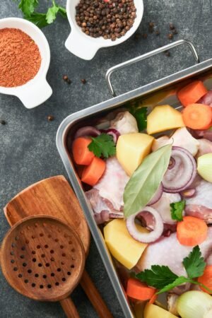 Cooking chicken bouillon or roast in cooking pan or pot with vegetables potatoes, carrots and herbs