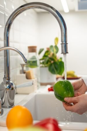 Different colourful fresh vegetables and fruits washing under water for healthy vegetarian eating