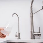 Woman get filtered water from stainless faucet into a glass